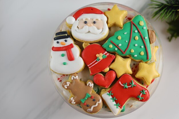 Biscuits de Noël décorés de glace royale dans une boîte en plastique à fond blanc.