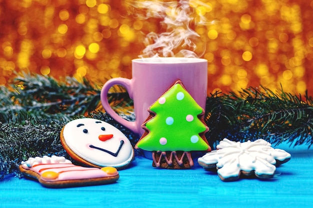 Biscuits de Noël et du Nouvel An près d'une tasse avec du thé ou du café chaud et des branches de sapin ambiance festive de Noël