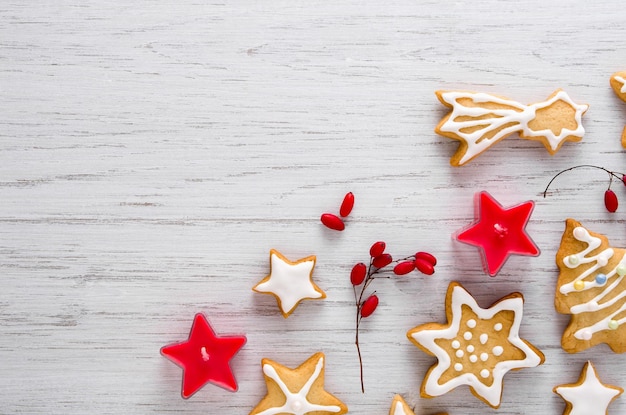 Biscuits de Noël faits maison avec glaçage blanc bougies rouges et baies sur fond de bois