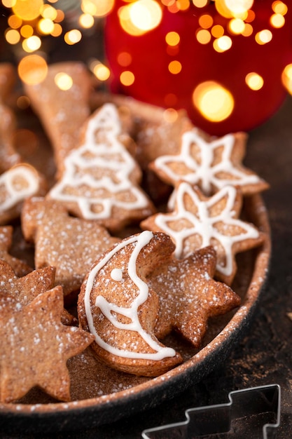 biscuits de Noël festifs décorés de glaçage et de sucre en poudre sur une assiette close up soft focus