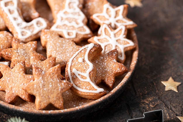 Biscuits de Noël festifs décorés de glaçage et de sucre en poudre sur une assiette close up soft focus