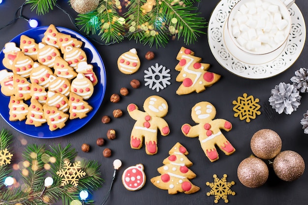 Biscuits de Noël savoureux, arbre de Noël, décorations sur fond noir. Concept de cuisine de Noël. Vue de dessus