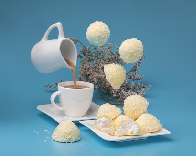 biscuits à la noix de coco sur un plat blanc sur fond bleu avec des objets volants et une tasse de café