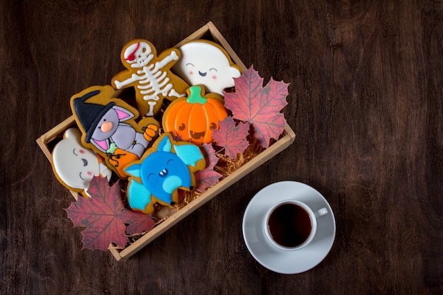Biscuits de pain d'épice drôles pour Halloween. Les gâteaux des fêtes se trouvent dans une boîte à côté d'une tasse de thé.