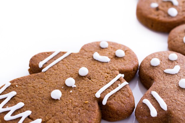 Biscuits de pain d'épice faits maison décorés de glaçage blanc sur fond blanc.