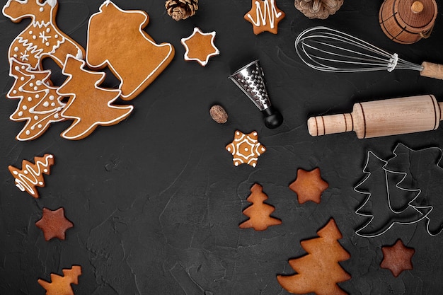 Biscuits de pain d'épice faits maison de Noël, épices et planche à découper sur fond sombre avec espace de copie pour la vue de dessus du texte. Concept de vacances, de célébration et de cuisine. Carte postale de nouvel an et de noël