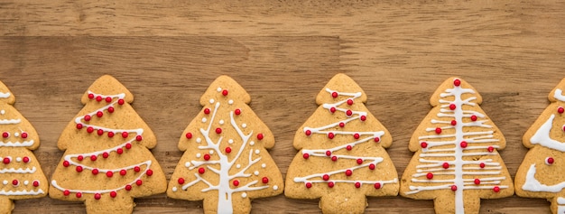 Biscuits de pain d&#39;épice forme arbre de Noël dans une rangée sur fond de bannière en bois