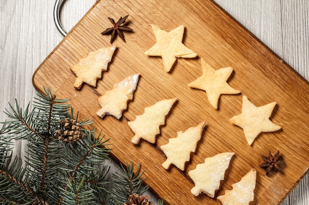 Biscuits de pain d'épice en forme d'arbre de Noël et d'étoile sur planche de bois