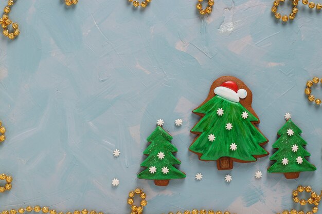 Biscuits de pain d'épice en forme d'arbres de Noël sur fond bleu clair, vue de dessus, gros plan