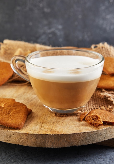 Photo biscuits de pain d'épice en forme de coeur avec une tasse de café cappuccino sur une planche de bois.