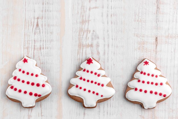 Biscuits de pain d'épice en forme de sapin de Noël sur un fond en bois texturé lumineux