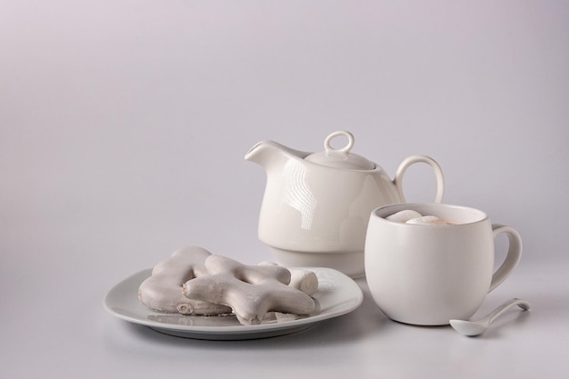 Biscuits de pain d'épice en glaçure blanche cacao théière blanche dans une tasse sur un espace de copie de fond blanc