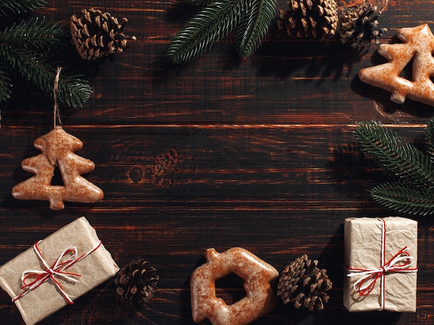 Biscuits de pain d'épice de Noël et des branches de pin et des cônes sur un fond en bois,