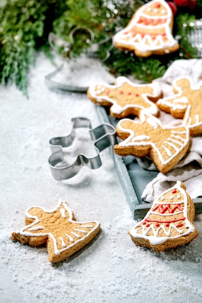 Biscuits de pain d'épice de Noël traditionnels faits maison avec glaçage orné Gingerbread Man, angel, bell avec des décorations de Noël sur une surface bokeh blanche.