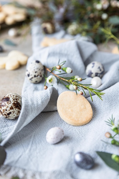 Biscuits de Pâques aux oeufs en forme de bonbons décor floral et oeufs de caille sur serviette en lin Concept de vacances