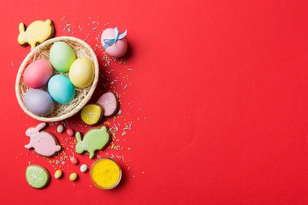 Biscuits de Pâques colorés dans un panier avec des oeufs de Pâques multicolores sur fond coloré Oeufs de Pâques de couleur pastel concept de vacances avec espace de copie