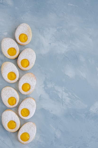 Biscuits de Pâques faits maison sous forme d'oeuf de Pâques avec du sucre en poudre et de la crème au citron sur un fond de béton bleu clair. carte de voeux. Fond de Pâques.