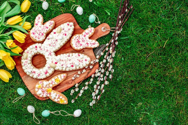 Biscuits de Pâques sur une planche de bois avec des décorations de Pâques sur l'herbe