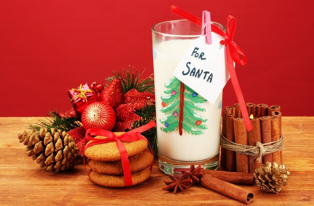 Biscuits pour le Père Noël: image conceptuelle de biscuits au gingembre, lait et décoration de Noël sur rouge