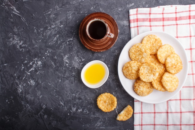 Biscuits de riz japonais traditionnel avec du miel et de la sauce soja sur une assiette en céramique blanche et une tasse de café