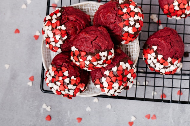 Biscuits ronds rouges décorés de poudre en forme de coeur pour la Saint-Valentin, sur une grille en métal noir, fond de pierre grise