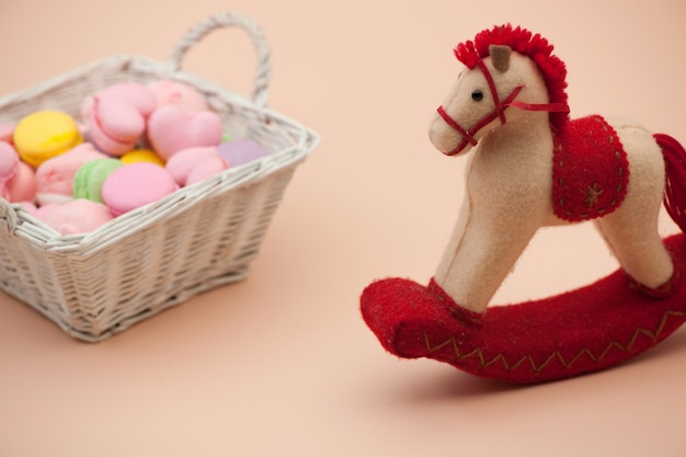 Biscuits roses et biscuits ronds colorés dans un panier en osier et un cheval jouet le jour de la Saint-Valentin