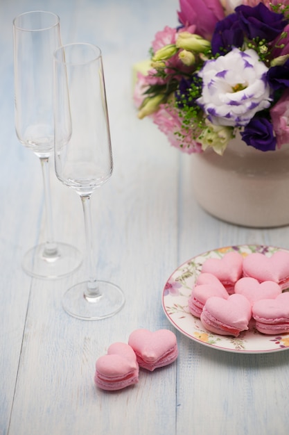 Biscuits roses en forme de coeurs sur une assiette et verres de champagne avec des fleurs