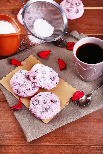 Biscuits roses et tasse de café sur une table en bois