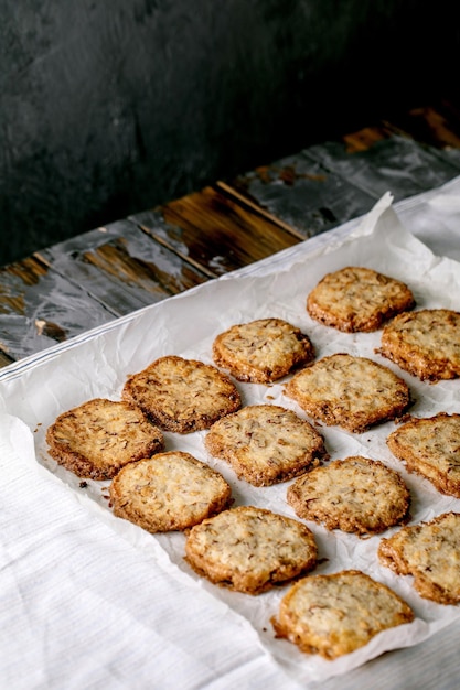 Biscuits sablés faits maison au sucre avec noix et chocolat blanc sur du papier sulfurisé sur un torchon en lin blanc sur une table en bois foncé. Pâtisserie maison.
