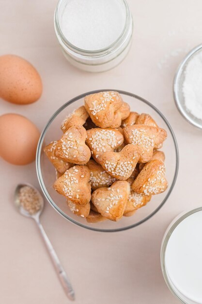 Biscuits sablés en forme de coeur faits maison avec des graines de sésame sur des œufs de table blancs sucre farine lait