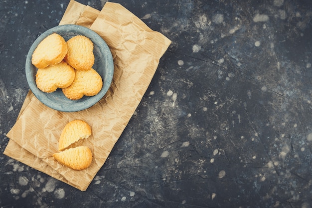 Biscuits sablés en forme de coeurs dans une petite assiette sur fond noir. Vue de dessus. Copiez l'espace.