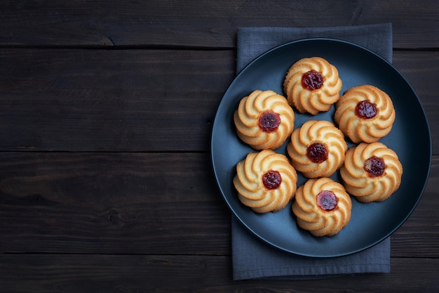 Biscuits sablés Kurabye avec confiture de baies dans une assiette noire Délicieux dessert fond en bois foncé avec espace de copie