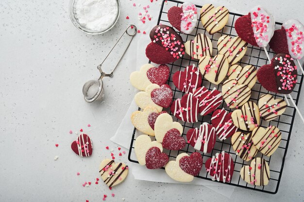 Biscuits de la Saint-Valentin Biscuits sablés à l'intérieur d'un coeur rouge sucré avec glaçage au chocolat sur une plaque rose sur fond gris Fête des mères Fête de la femme Vacances douces cuisson Carte de la Saint-Valentin Vue de dessus