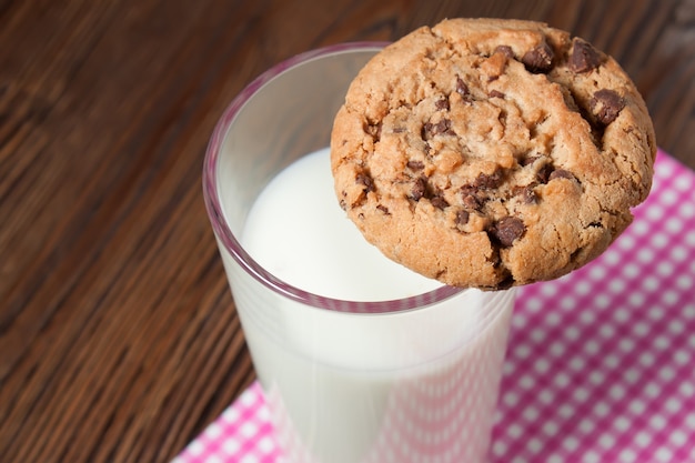 Biscuits savoureux et verre de lait sur fond de bois rustique