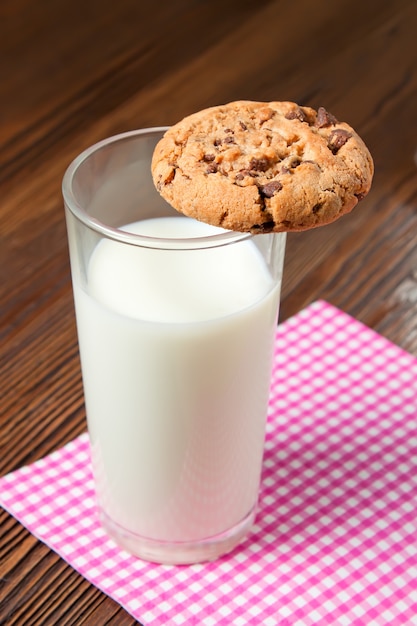 Biscuits savoureux et verre de lait sur fond de bois rustique