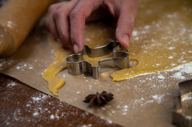 Les biscuits sont découpés dans la pâte roulée sous la forme d'un homme, la main du chef pâtissier tient un biscuit...