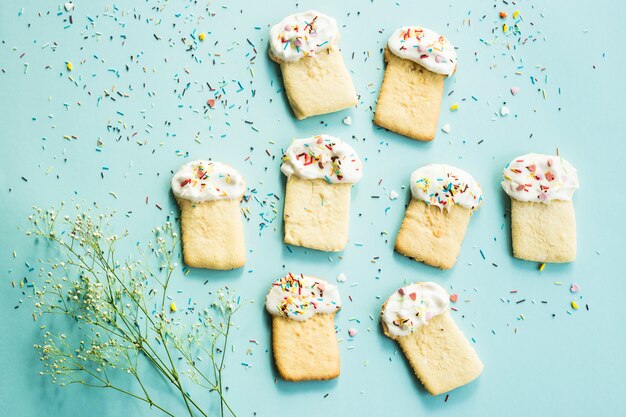 Biscuits sous forme de gâteaux de Pâques sur fond bleu parmi les fleurs de gypsophila