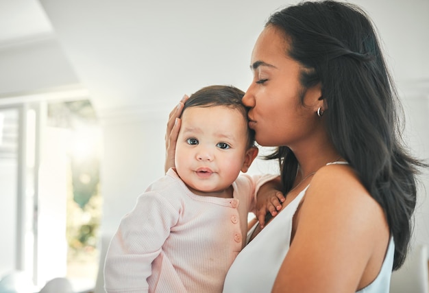 Bisous pour mon bébé. Photo recadrée d'une jeune femme séduisante et de son nouveau-né à la maison.