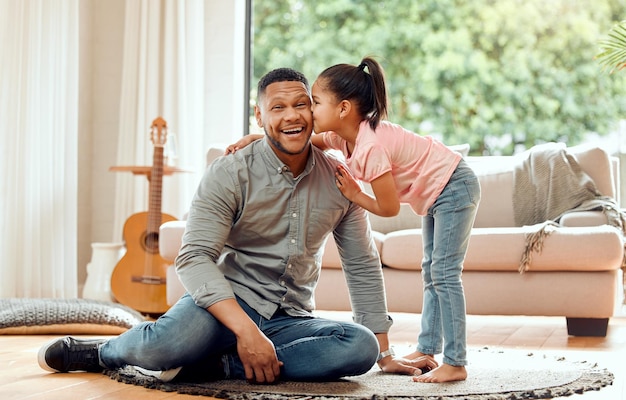 Bisous surprises pour le papa numéro un mondial. Portrait d'un jeune père et fille se liant ensemble à la maison.