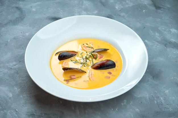 Bisque de soupe à la crème française aux fruits de mer en assiette blanche sur fond gris