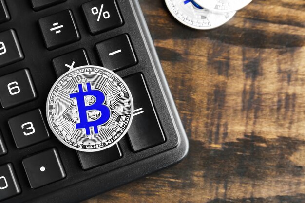 Bitcoin argent avec calculatrice sur fond de bois