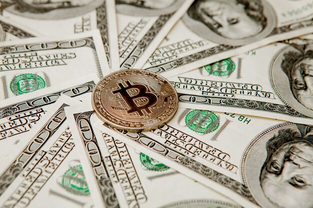 Bitcoin doré sur les billets d'un dollar américain. Concept d'échange de monnaie électronique