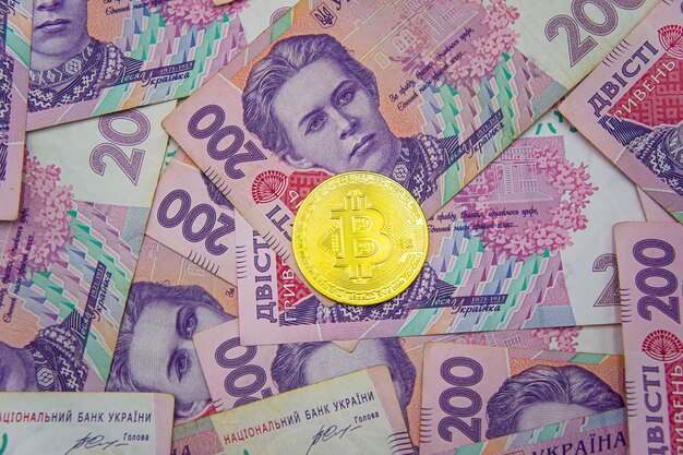 Bitcoin doré sur fond de deux cents factures de hryvnia ukrainienne