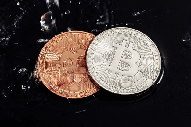 Bitcoin sur fond noir. Blanchiment de Bitcoin avec de l'eau. Crise économique.