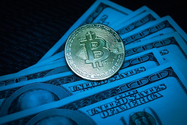 Bitcoin d'or sur des billets de cent dollars en gros plan