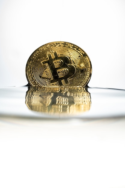 Bitcoin d&#39;or avec des éclaboussures d&#39;eau sur fond blanc