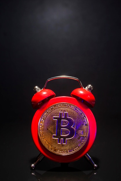 Photo bitcoin et réveil sur fond noir concept de date limite pour investir dans la crypto-monnaie bitcoin