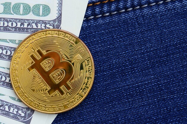 Les bitcoins et les billets d&#39;un dollar doré reposent sur un tissu de jeans. Nouvelle monnaie virtuelle. Nouvelle crypto-monnaie sous forme de pièces