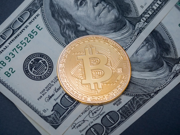 Des bitcoins dorés reposent sur des billets de 100 dollars