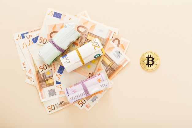 Bitcoins d'or avec des billets en euros en arrière-plan.